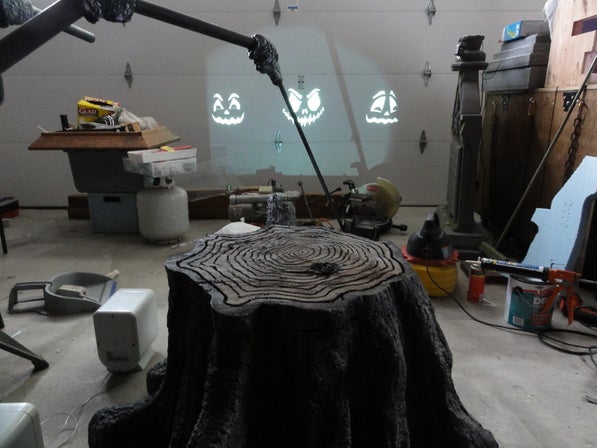 Back view of tree stump showing projector beam running the singing pumpkins display